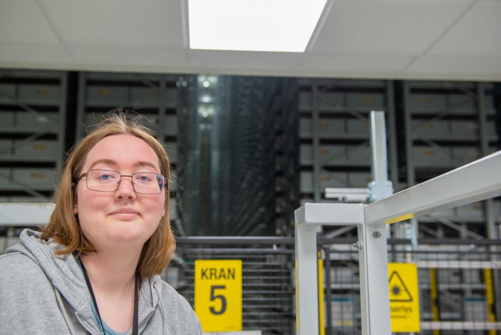 portrett av kvinnlig medarbeider ved nasjonalbiblioteket i mo i rana på innsiden av fjellmagasinet foran en løftekran. foto.
